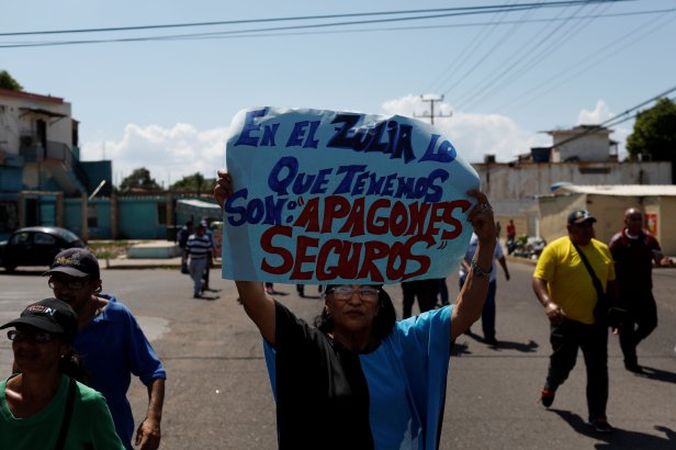 A woman holds a banner that reads "In Zulia what we have are blackouts for granted" during a protest in Maracaibo